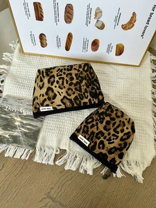 Dettaglio di borse per cosmetici in tela leopardata con etichette su tessuto di lino