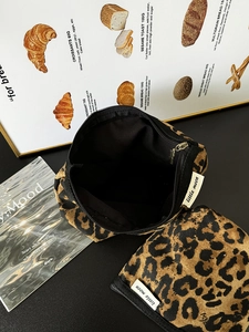 Dettaglio di due borse per cosmetici in tela con stampa leopardata e cerniere nere