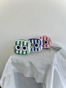 Detailed view of three mini canvas coin purses with striped patterns and eye embroidery