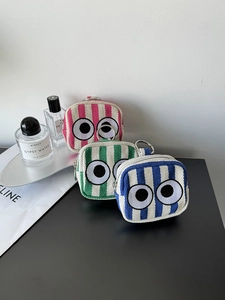 Detailed view of striped canvas mini pouches with signature eye embroidery and metal hooks