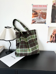Detail of a large checkered wool tote bag in autumn colors on a vintage cabinet