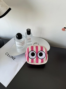 Close-up of pink striped canvas mini pouch featuring embroidered big eyes and metal clasp