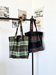 Detail of vintage plaid wool tote bags in brown and blue hanging on a minimalist rack