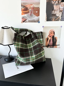 Detail of vintage brown-green plaid wool tote bag with wide shoulder strap in home setting