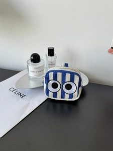 Detailed view of the striped mini pouch featuring cartoon eye embroidery and silver zipper