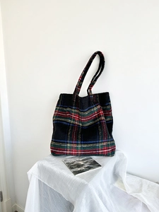 Close-up of a colorful wool plaid tote bag with sturdy handles on a soft white background