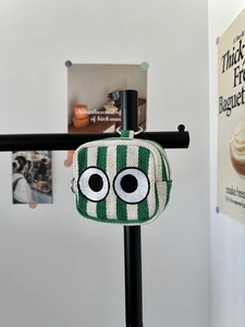 Mini canvas pouch with green and white stripes and eye embroidery hanging on a metal rack