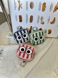 Close-up of mini striped canvas coin pouches with embroidered eyes and metal ring