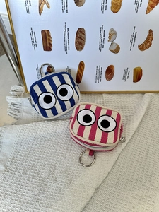 Detailed view of striped canvas mini pouches with eye embroidery and metal ring hooks