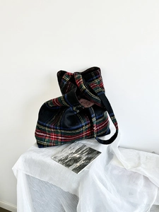 Detail of tartan wool plaid tote bag on white stool with magazine for winter style