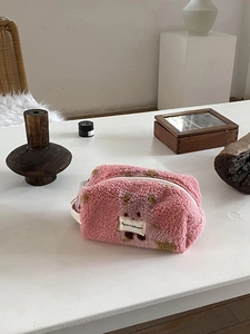 Detailed macro of pink plush makeup bag with teddy bear pattern and carrying handle