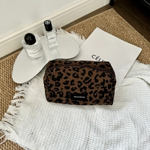 Close-up of leopard print corduroy makeup bag texture with brand label and top zipper