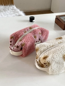 Close-up of plush lamb wool makeup bags with brown heart patterns and white handles