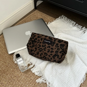 Close-up of leopard print corduroy makeup bag with gold zipper on a white blanket