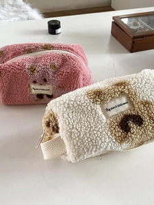 Close-up of plush sherpa makeup bags with bear patterns and secure zipper closure