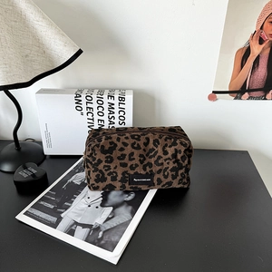 Chic leopard print corduroy makeup bag with zipper closure on a stylish desk setup