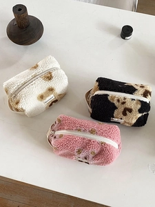 Detailed view of plush makeup bags with leopard and dot patterns on a white table