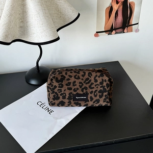 Macro detail of leopard print corduroy makeup bag with secure zipper and woven label tag