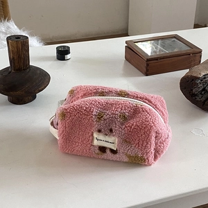Pink plush travel makeup bag with brown polka dots and zipper closure for storage