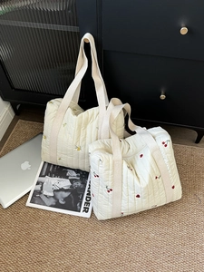 Detail of cream quilted tote bags featuring delicate cherry and lemon embroidery