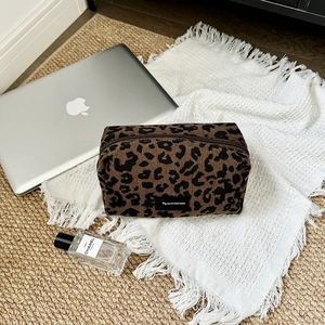 Leopard print corduroy cosmetic bag with large capacity and zipper closure on white fabric