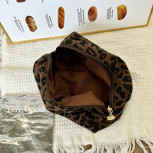 Leopard print corduroy makeup bag with gold zipper on a decorative white napkin