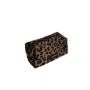 Leopard print corduroy makeup bag with zipper closure and brand label on white background