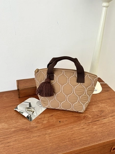 Dettaglio borsa tote kaki con trapuntatura a onde, manici marroni e nappina decorativa