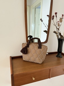 Dettaglio della borsa shopper trapuntata kaki con nappa decorativa e cuciture curve