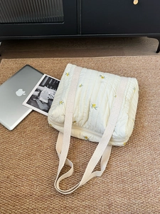 Detailed view of quilted cotton tote bag with small yellow floral embroidery and zip closure