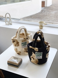 Detail of plush teddy bucket bag featuring GOOD LUCK patch in cream and black wool