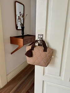 Dettaglio di una borsa trapuntata con ricamo a onde e nappa marrone scuro