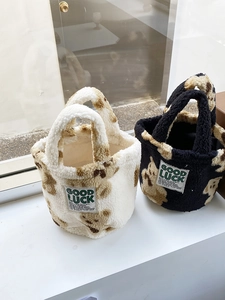Close-up of plush teddy bear bucket bags with Good Luck patch and fuzzy textures