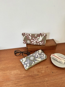 Detailed embroidery of floral and bird patterns on linen-style zippered organizer pouches