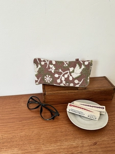 Macro view of detailed plant and bird embroidery on a rustic canvas organizer bag