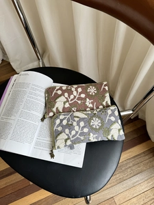 Detail of embroidered floral fabric organizer bags with vintage metal zippers on a book