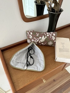 Close-up of floral embroidery on a brown storage pouch with a checkered fabric lining