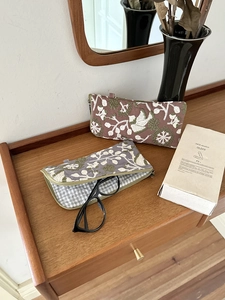 Detail of vintage floral embroidered pouches showing storage for black frame glasses