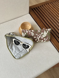 Detail of embroidered floral pouch with green zipper and soft checkered inner lining