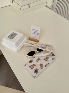 Detailed view of a white quilted storage pouch with bear pattern holding sunglasses