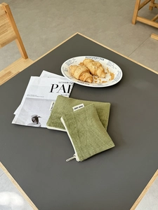 Makroaufnahme von zwei grünen Cord-Kosmetiktaschen mit Reißverschluss und Stoffetiketten