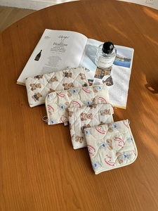 Quilted cotton cosmetic bags with cute bear and poodle prints on a wooden table