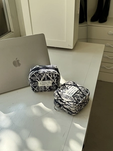 Detail of blue and white embroidered fabric pouches with metal ring zippers on a desk
