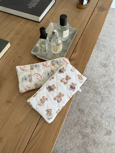 Detailed view of quilted cotton pouches featuring cute teddy bear patterns on a wooden desk