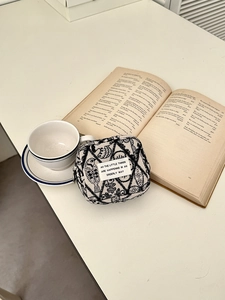 Detail of embroidered canvas mini pouch with abstract patterns on lifestyle desktop