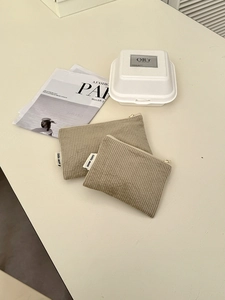 Makroaufnahme von zwei khakifarbenen Cord-Kosmetiktaschen mit Metallreißverschluss und Label