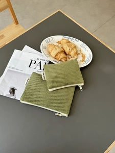 Detail von grünem Cord-Kosmetiktaschen-Set mit Silberreißverschluss und Stoffetikett