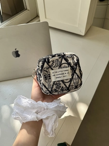 Detail of embroidered canvas pouch with vintage bird pattern and circular silver zipper