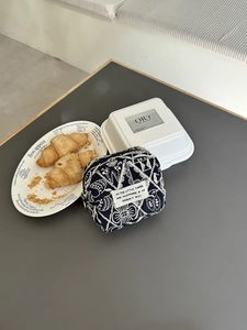 Detailed close-up of blue canvas pouch with white embroidery and zip on a table
