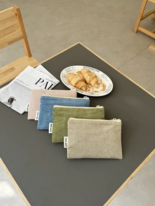 Cord-Kosmetiktaschen in vier Farben auf Tisch mit Croissants und Zeitungen